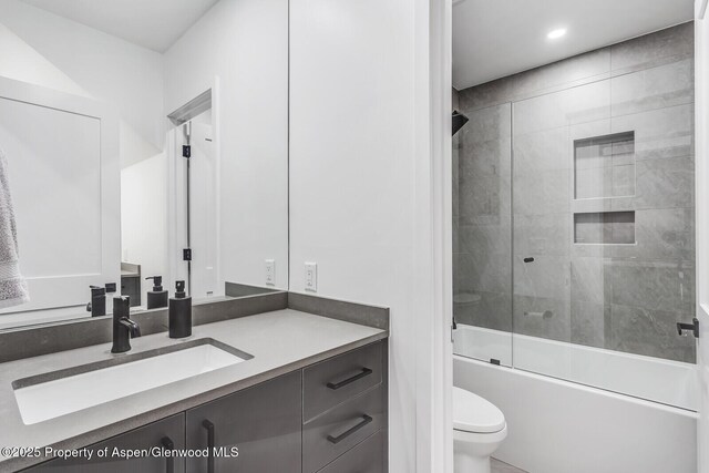 full bathroom with combined bath / shower with glass door, vanity, and toilet