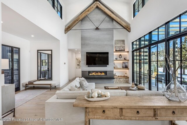 living room with light wood-type flooring, a fireplace, and a high ceiling