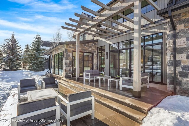 snow covered patio featuring an outdoor living space and a pergola