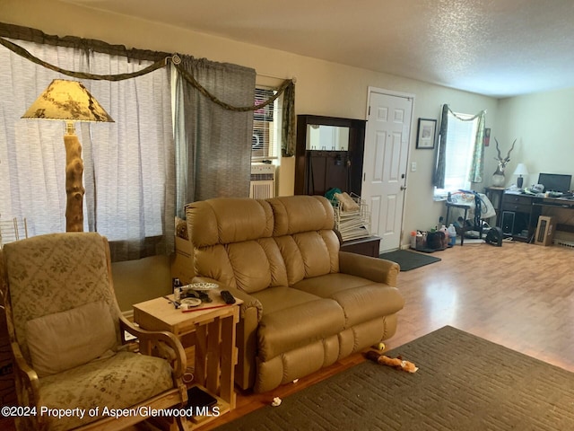 living room featuring hardwood / wood-style flooring, cooling unit, and a textured ceiling