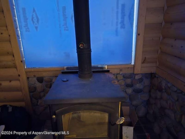 interior details featuring a wood stove and rustic walls