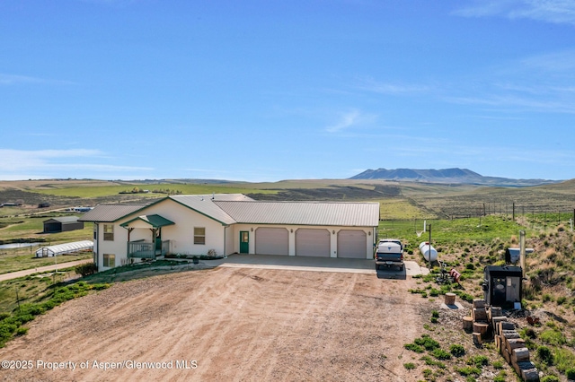 1210 County Road 103, Craig, CO 81625 - ranch-style house with an attached garage, driveway, metal roof, a mountain view, and a view of rural / pastoral area