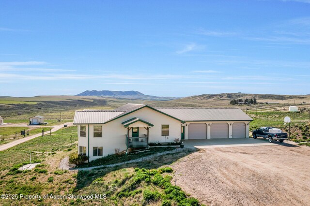 1210 County Road 103, Craig, CO 81625 - view of front of house featuring dirt driveway, a garage, a mountain view, and metal roof