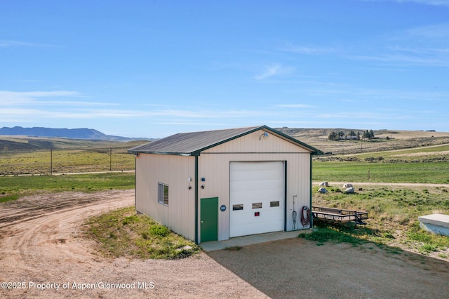 1210 County Road 103, Craig, CO 81625 - detached garage featuring a mountain view, driveway, and a view of countryside
