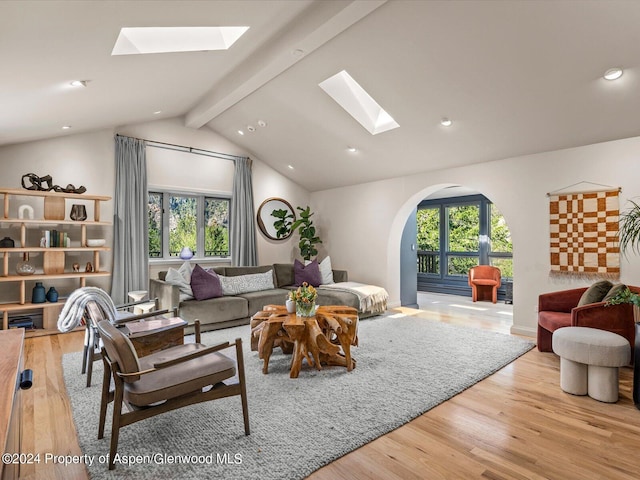 living room featuring vaulted ceiling with skylight and light hardwood / wood-style floors