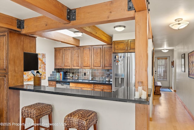 124 W Hyman Ave Unit 3B, Aspen, CO 81611 - kitchen featuring appliances with stainless steel finishes, dark countertops, brown cabinets, backsplash, and light wood-type flooring