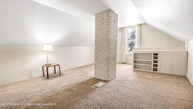 additional living space with vaulted ceiling, ornate columns, and carpet flooring