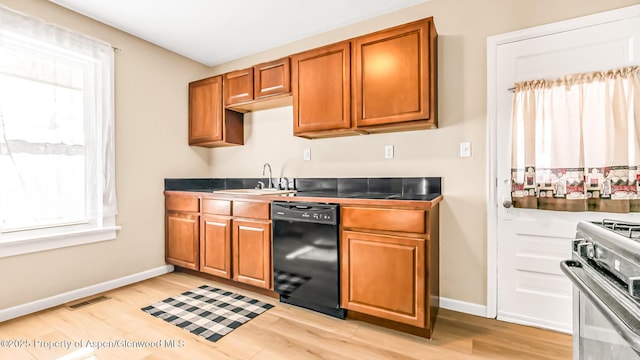 kitchen featuring light wood-type flooring, sink, black dishwasher, and stainless steel gas range oven