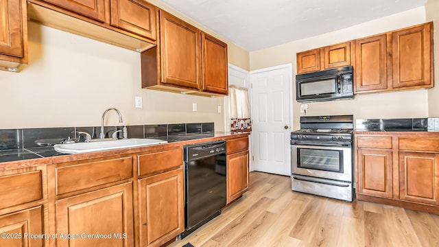 kitchen with sink, black appliances, and light hardwood / wood-style floors