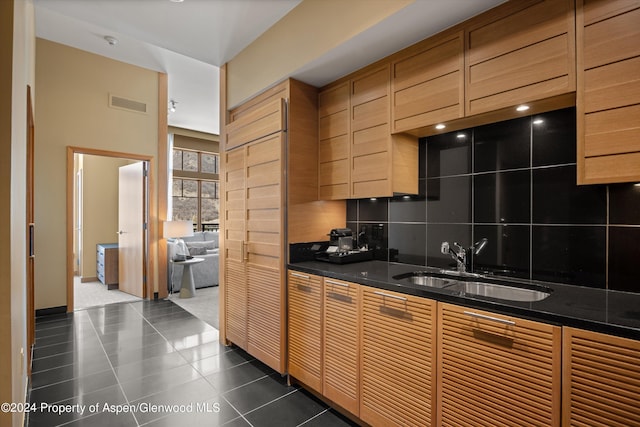 kitchen with decorative backsplash, dark tile patterned floors, and sink