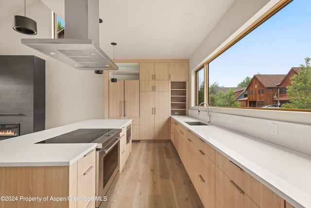 kitchen featuring sink, electric range, island range hood, light brown cabinetry, and decorative light fixtures