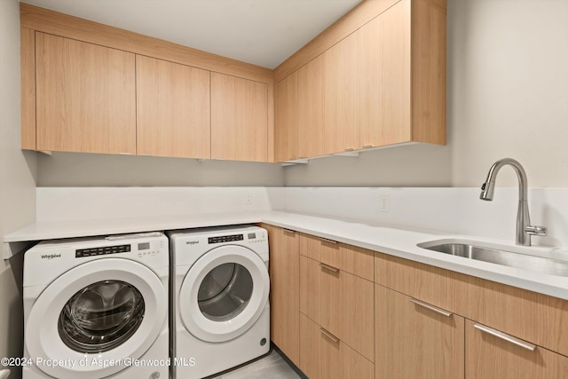 washroom with cabinets, washer and clothes dryer, and sink