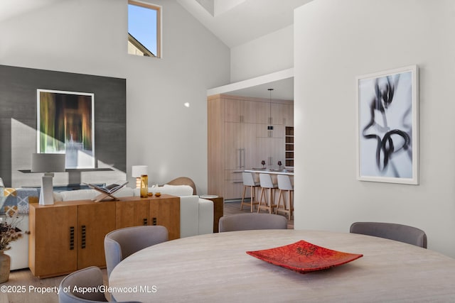 dining area with high vaulted ceiling and hardwood / wood-style floors