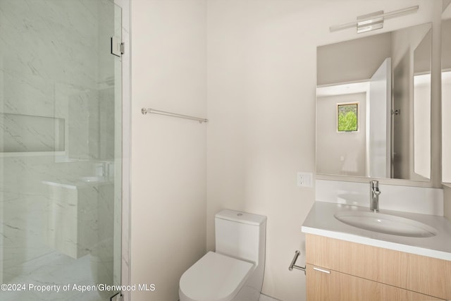 bathroom featuring a shower with door, vanity, and toilet