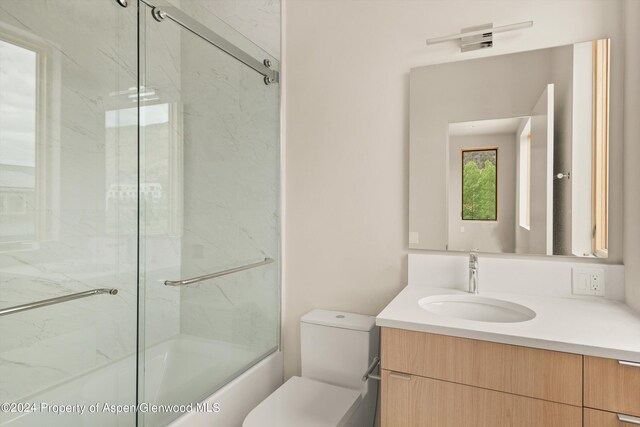 full bathroom with vanity, shower / bath combination with glass door, and toilet