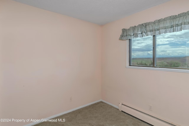 spare room featuring light colored carpet and a baseboard heating unit