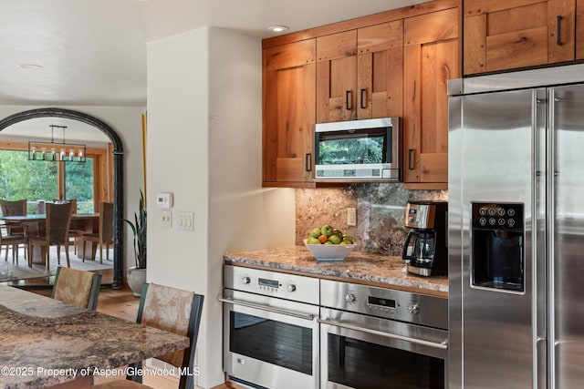 554 Sinclair Rd, Snowmass Village, CO 81615 - kitchen with appliances with stainless steel finishes, brown cabinetry, decorative backsplash, and stone countertops