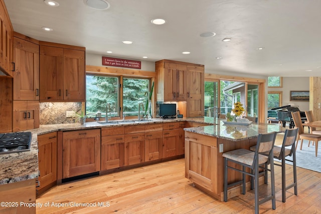 554 Sinclair Rd, Snowmass Village, CO 81615 - kitchen featuring stainless steel gas stovetop, a kitchen bar, recessed lighting, light wood-type flooring, and light stone countertops