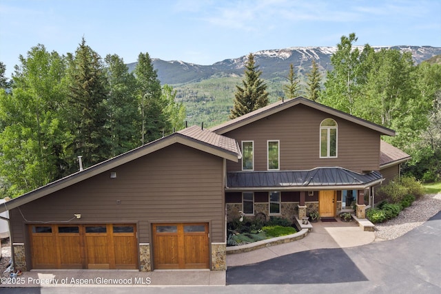 554 Sinclair Rd, Snowmass Village, CO 81615 - view of front facade with stone siding, a mountain view, asphalt driveway, and covered porch