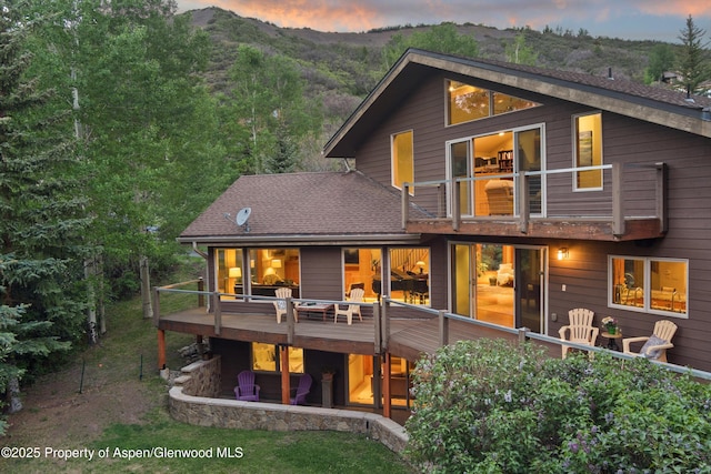 554 Sinclair Rd, Snowmass Village, CO 81615 - back of house at dusk featuring a wooden deck, a shingled roof, and a balcony