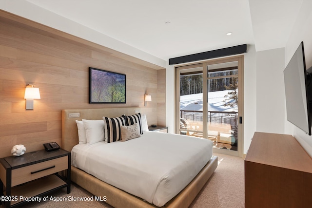 carpeted bedroom featuring access to outside and wood walls