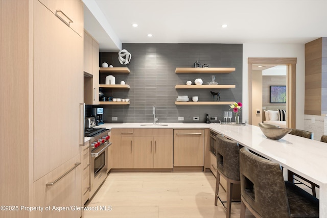 bar with light brown cabinets, sink, tasteful backsplash, light hardwood / wood-style floors, and stainless steel appliances