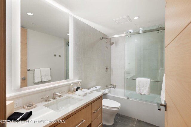 full bathroom with tile patterned floors, vanity, toilet, and shower / bath combination with glass door