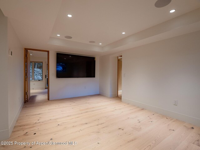 unfurnished room featuring recessed lighting, baseboards, a tray ceiling, and light wood finished floors