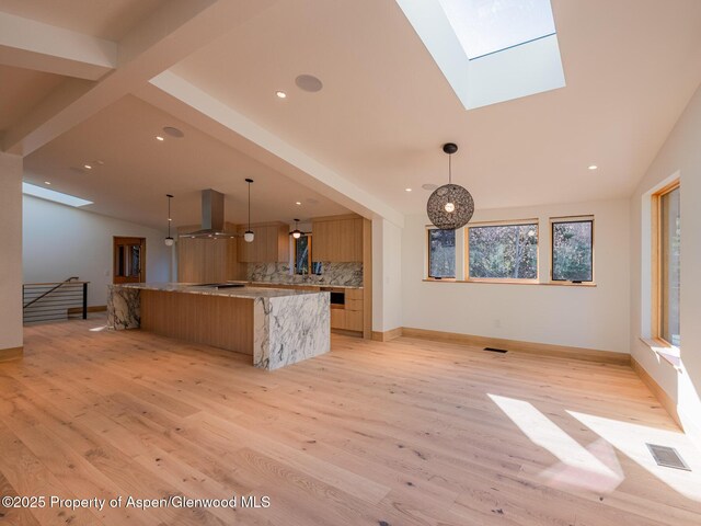 kitchen with decorative backsplash, exhaust hood, visible vents, and open floor plan