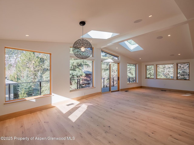 unfurnished dining area with baseboards, light wood finished floors, plenty of natural light, and vaulted ceiling with skylight