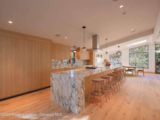 51 Roaring Fork Dr, Aspen, CO 81611 - kitchen with island range hood, modern cabinets, a large island, decorative backsplash, and light wood-style flooring