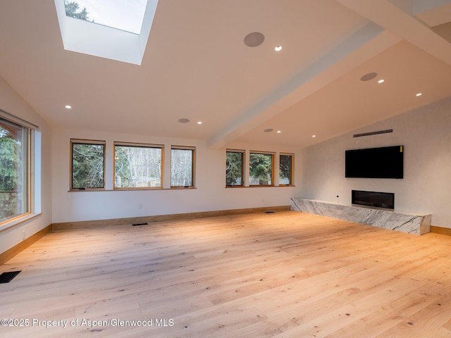unfurnished living room with wood-type flooring, vaulted ceiling with skylight, and a wealth of natural light
