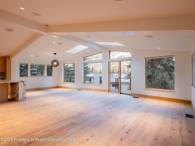unfurnished living room featuring baseboards, lofted ceiling with skylight, light wood-style flooring, and visible vents