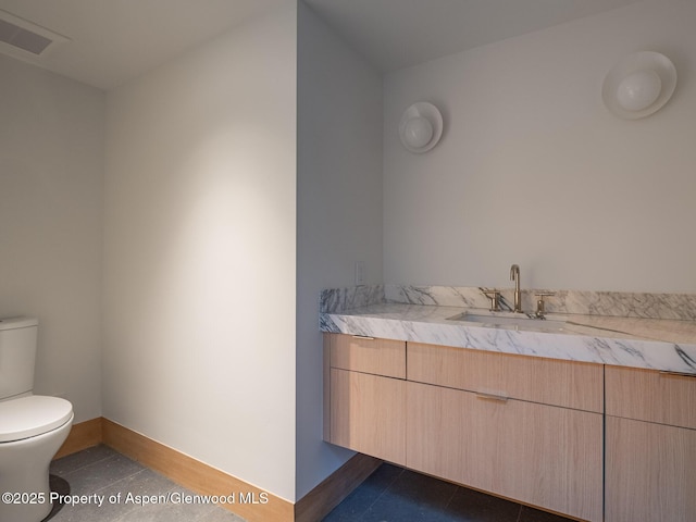 half bathroom featuring vanity, baseboards, toilet, and visible vents