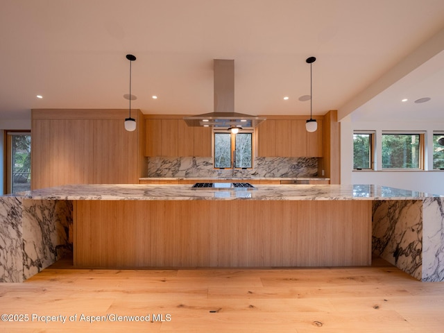 kitchen featuring tasteful backsplash, island range hood, and light wood-style floors
