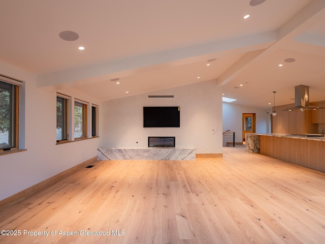 unfurnished living room featuring plenty of natural light, recessed lighting, vaulted ceiling with beams, and light wood-type flooring