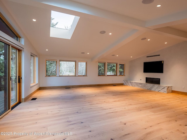 unfurnished living room featuring light wood-style flooring, baseboards, a healthy amount of sunlight, and lofted ceiling with skylight