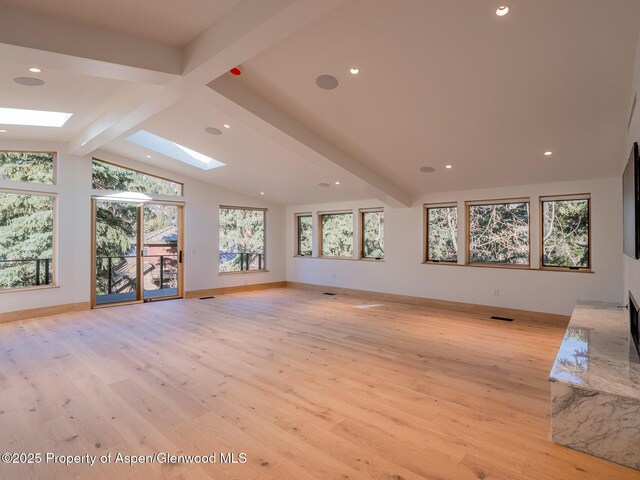unfurnished living room with recessed lighting, light wood-style flooring, baseboards, and vaulted ceiling with skylight