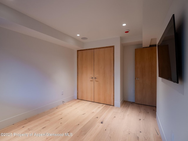 unfurnished bedroom with light wood-type flooring, recessed lighting, baseboards, and a closet