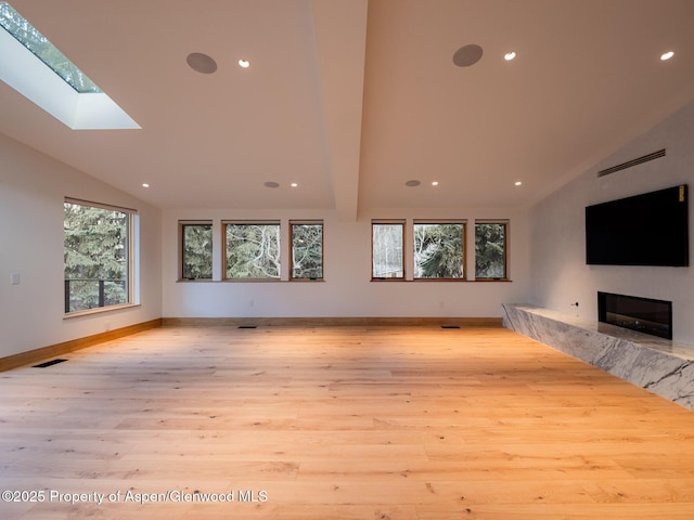 unfurnished living room featuring a fireplace, lofted ceiling with skylight, wood finished floors, and visible vents