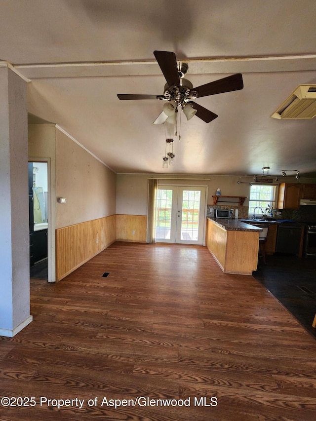 449 County Road 223, Rifle, CO 81650 - unfurnished living room with wainscoting, dark wood-style floors, vaulted ceiling, a ceiling fan, and wooden walls