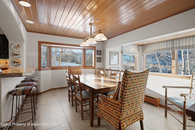 dining space with baseboard heating, wood ceiling, baseboards, and light tile patterned floors