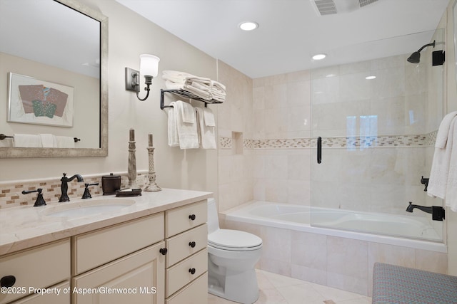 full bath featuring toilet, tile patterned floors, tiled shower / bath combo, vanity, and backsplash