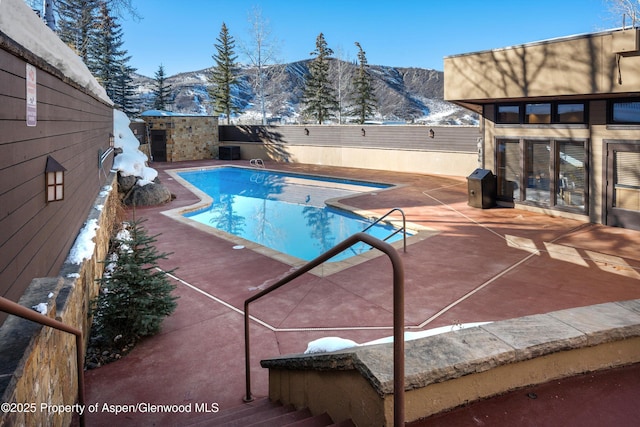 view of pool featuring a patio area, a fenced backyard, a mountain view, and a fenced in pool