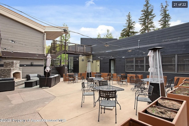 view of patio featuring an outdoor living space with a fireplace and a balcony