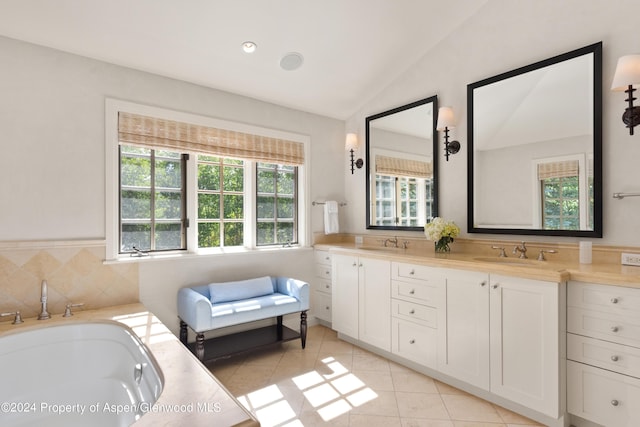 bathroom featuring a bathing tub, vanity, lofted ceiling, and tile patterned floors