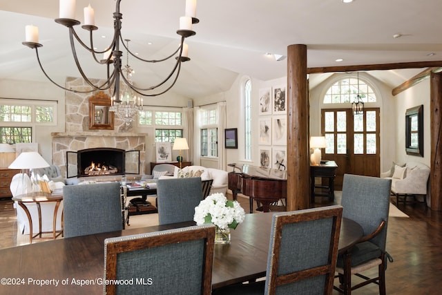 dining area featuring french doors, a notable chandelier, hardwood / wood-style floors, vaulted ceiling, and a fireplace