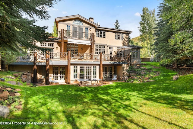 back of house featuring french doors, a deck, a patio area, and a lawn