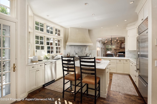 kitchen with kitchen peninsula, premium range hood, tasteful backsplash, and stainless steel appliances