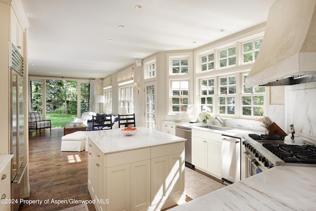 kitchen featuring stainless steel appliances, light stone counters, white cabinets, and extractor fan